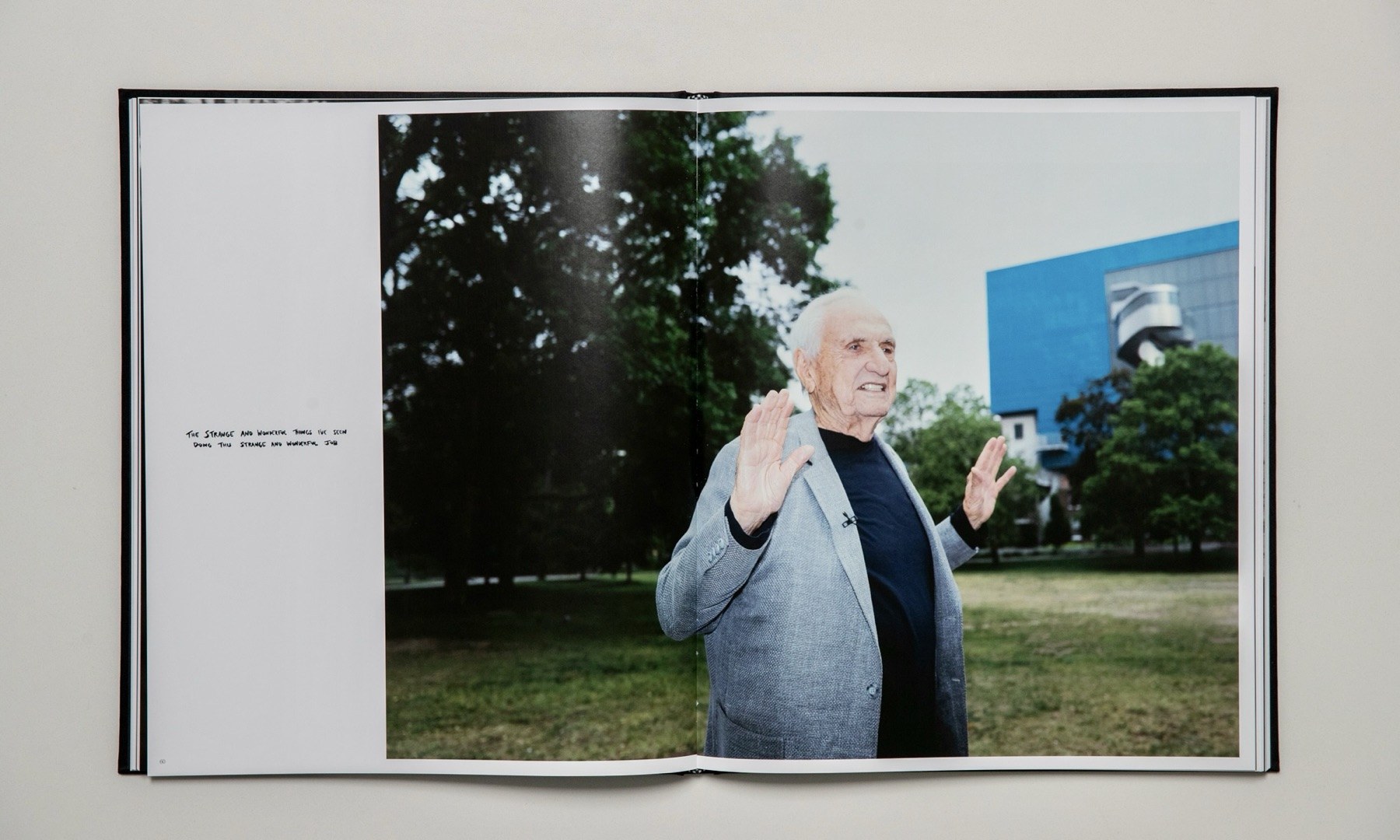 Open spread: a smiling older man in a grey jacket raising a hand in a park